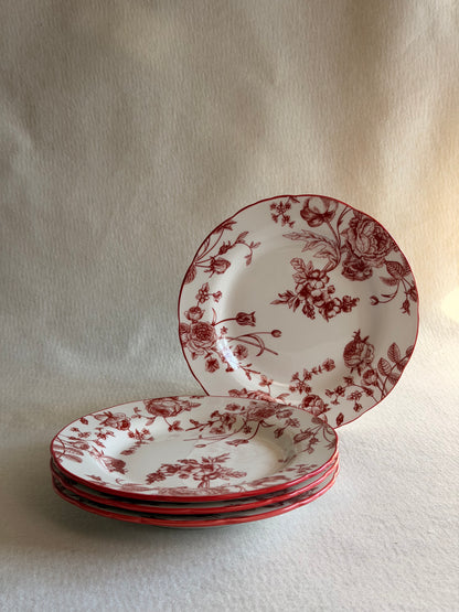 Set of ceramic plates with red floral patterns on a light wooden surface