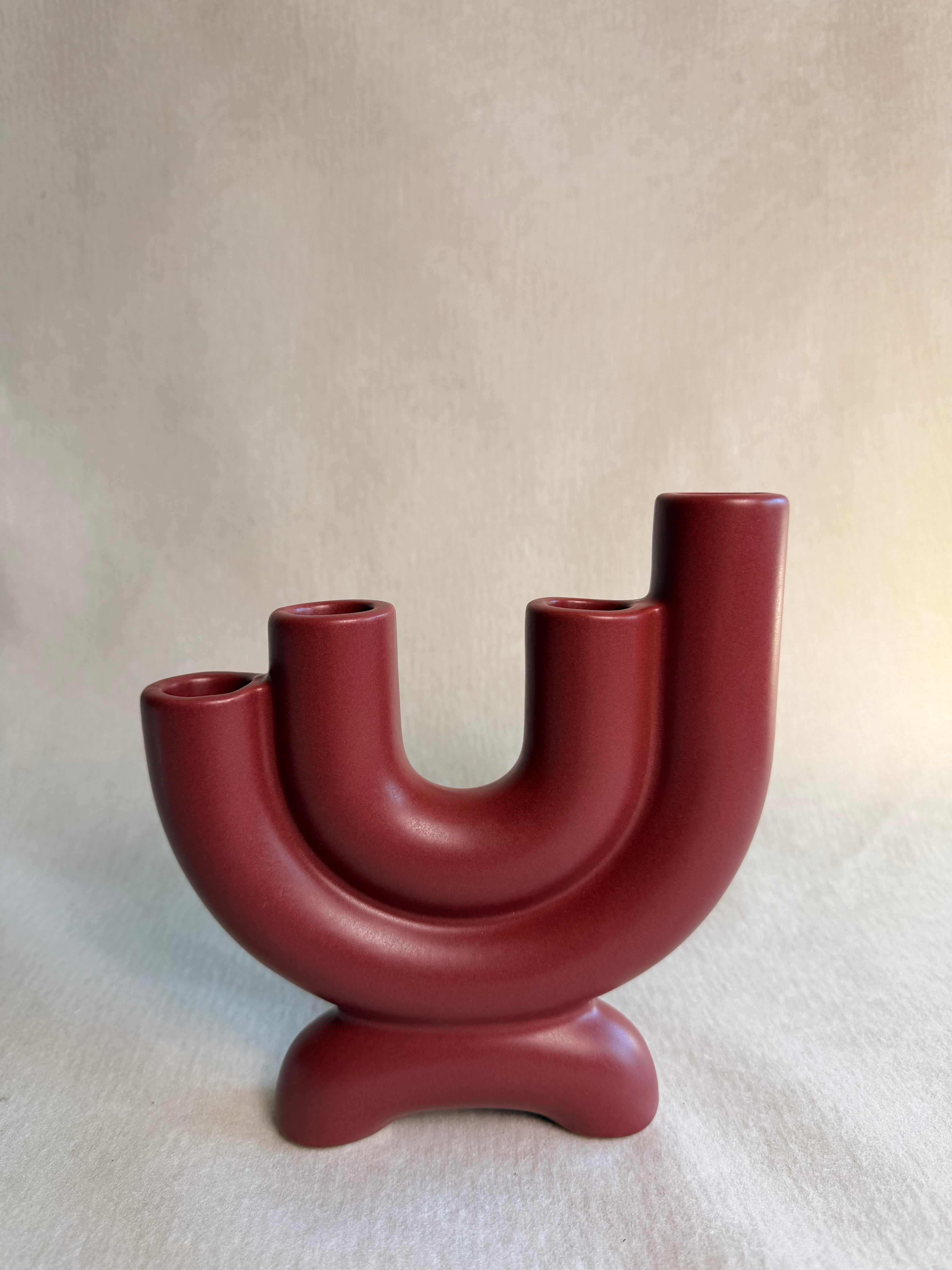 Deep red Ember ceramic candelabra with U-shaped twin arms and footed base against a neutral cloth.