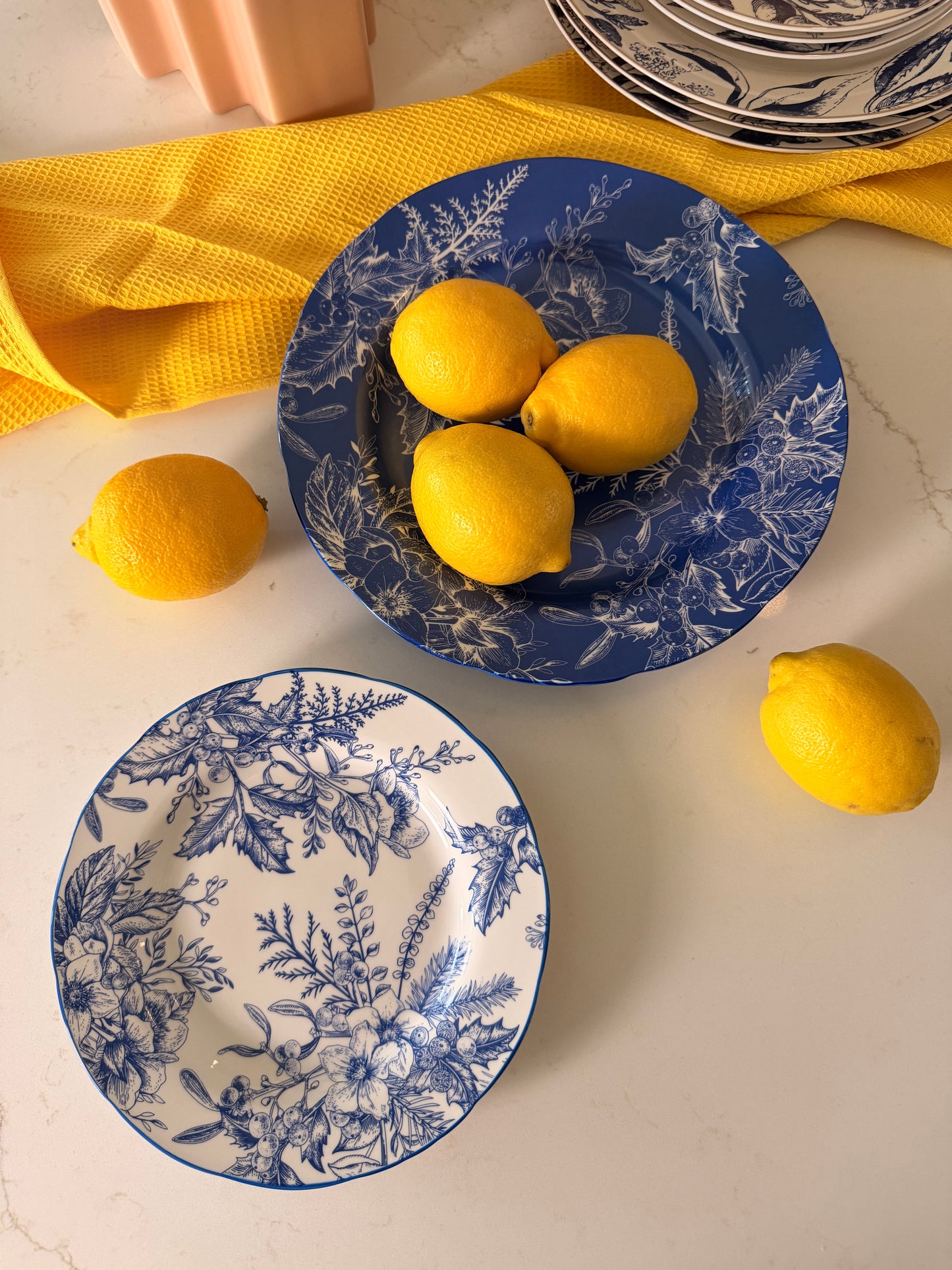 Coastal Chinoiserie blue and white floral plates styled with fresh lemons and yellow linen on marble.