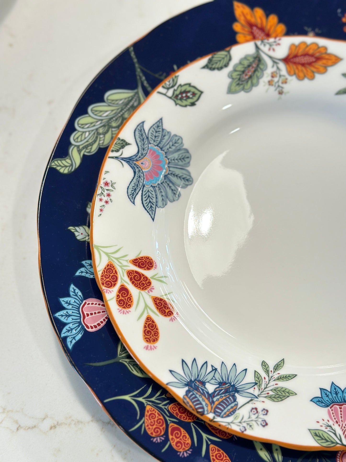 Close-up of the navy rim and colorful floral pattern on the Azure Desert Floral pasta plates.