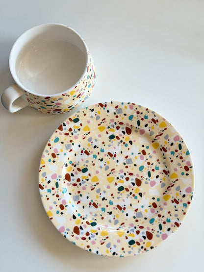Colorful terrazzo-patterned tea cup and saucer on a white background