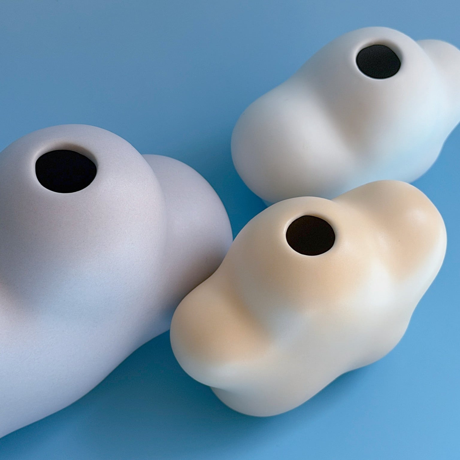 Three white ceramic vases on a light blue background
