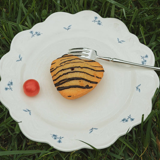 Heart-shaped dessert with a cherry on a decorative plate on grass
