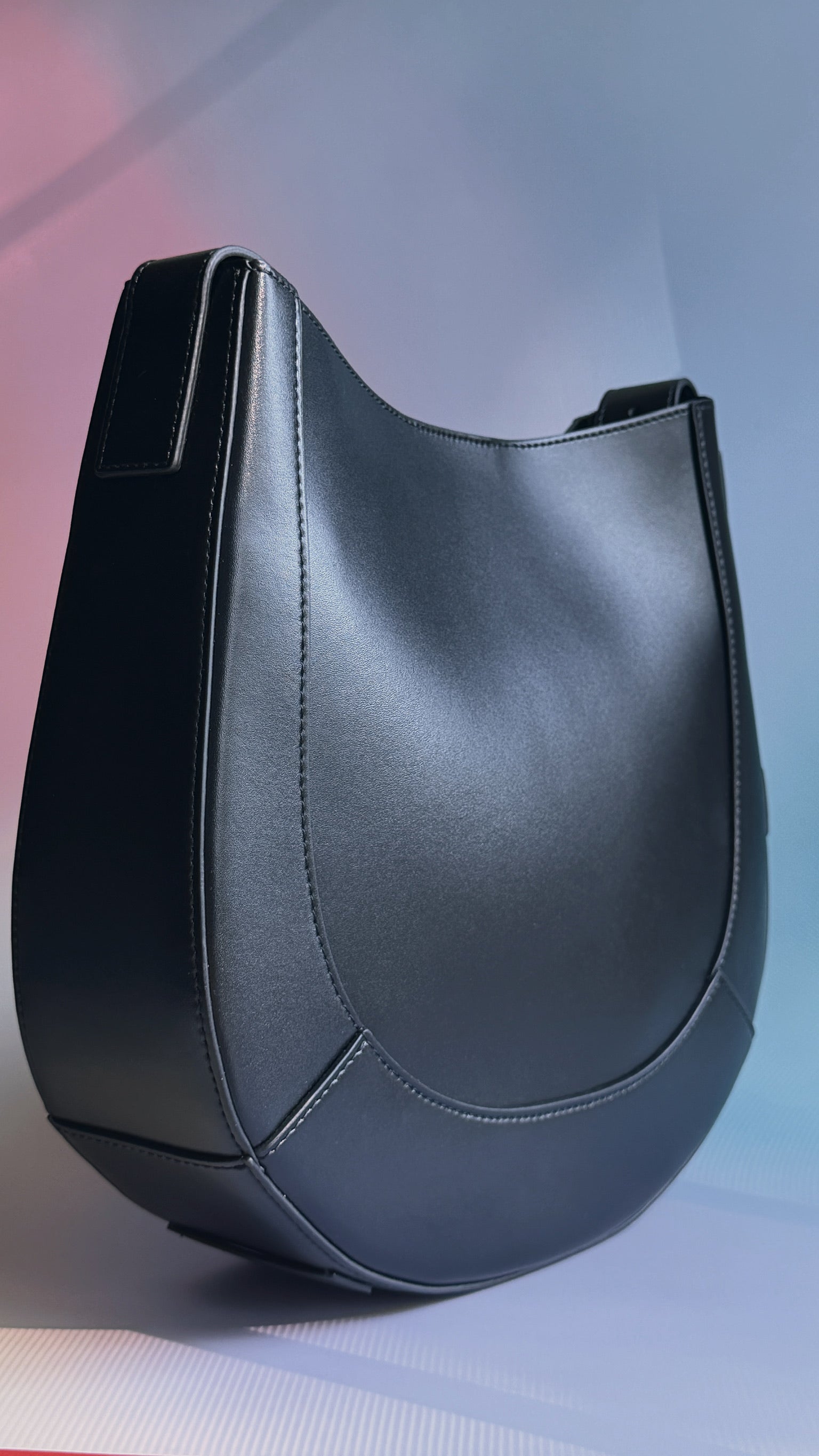 Curved leather saddle bag with structured silhouette and adjustable strap
