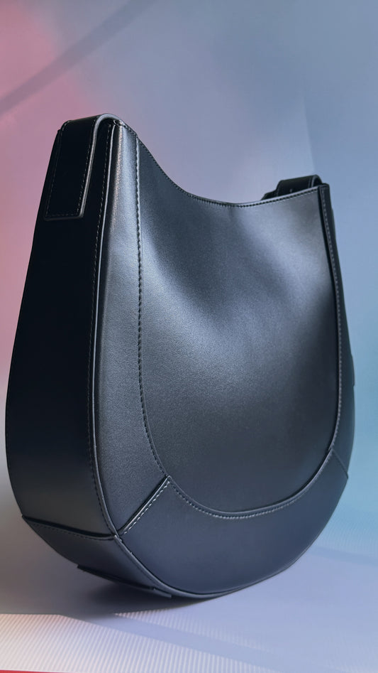Curved leather saddle bag with structured silhouette and adjustable strap