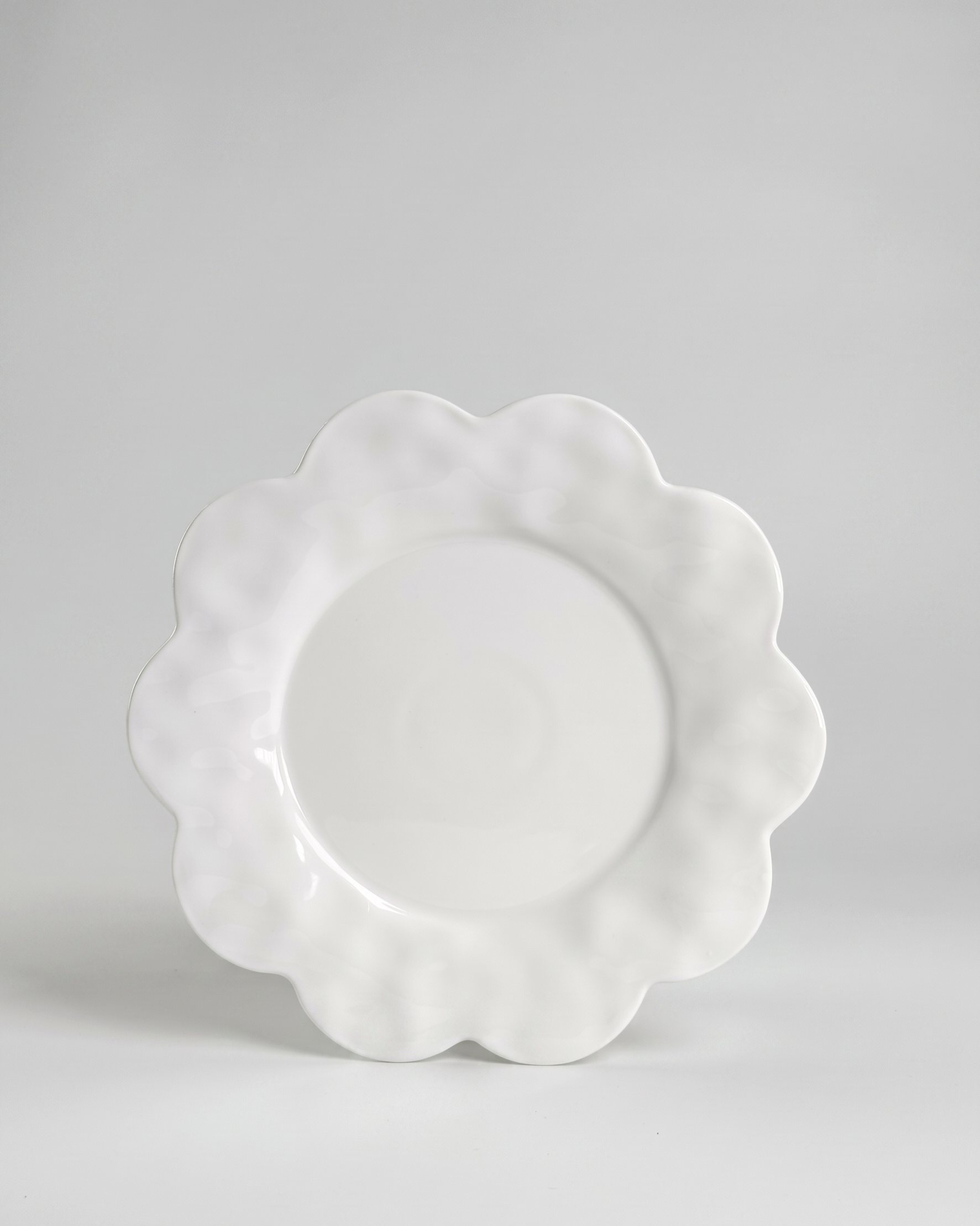 scalloped white saucer plate on gray background