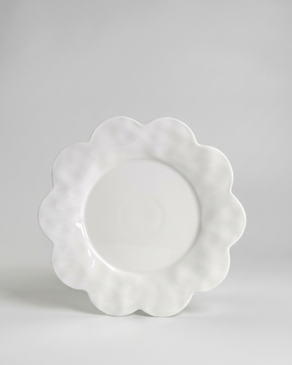 scalloped white saucer plate on gray background