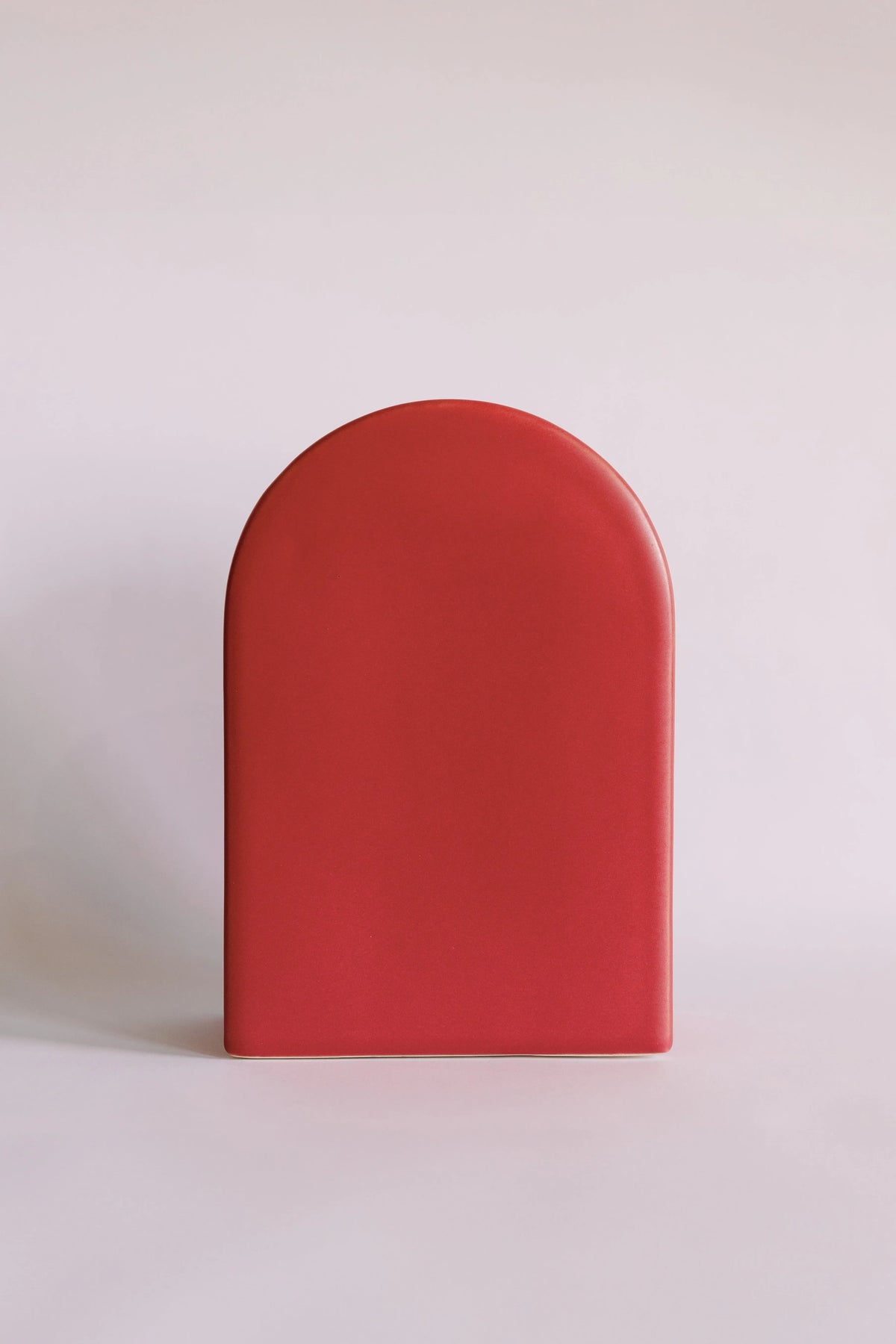 Arch Deco ceramic vase in matte coral red, tall rounded-arch shape viewed straight on