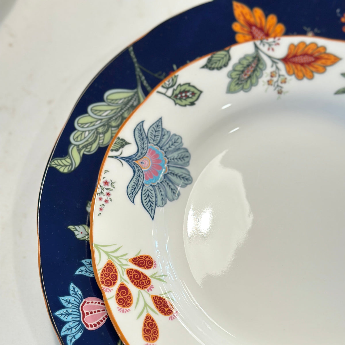 Close-up of the navy rim and colorful floral pattern on the Azure Desert Floral pasta plates.