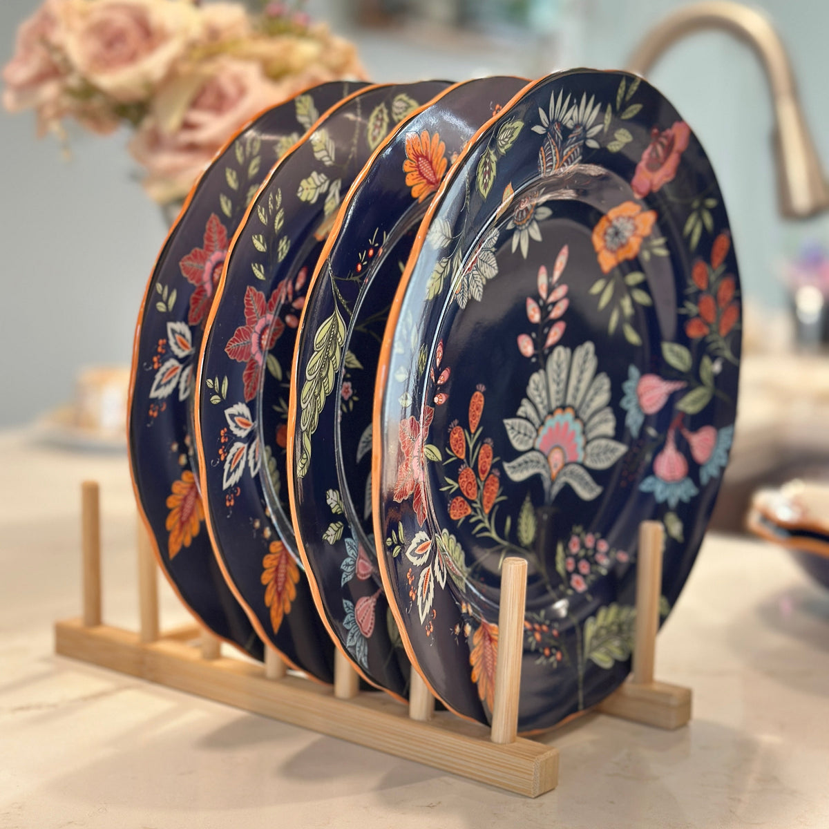 Azure Desert Floral pasta plates with navy and orange floral pattern stacked on a wooden plate rack.