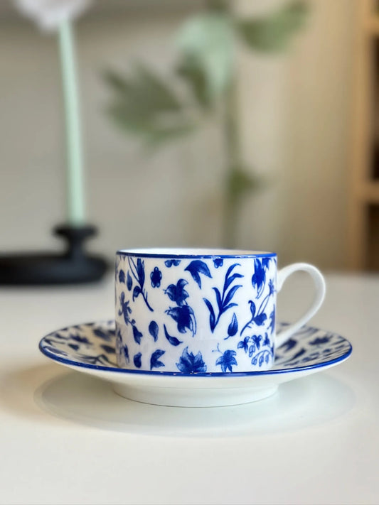 Blue floral porcelain mug and saucer styled on a table beside a candle holder