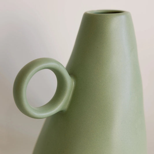 Sage green conical ceramic bud vase with a round loop handle, matte glaze, close-up of the tapered body and ring handle