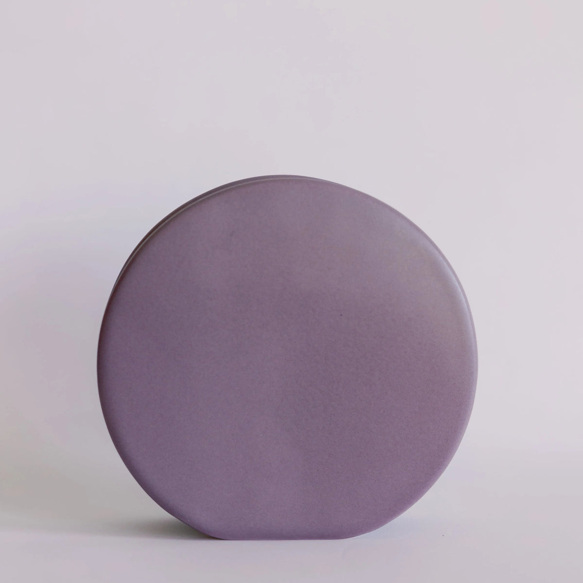 Ceramic circle bud vase in matte lavender, flat disc-shaped silhouette against pale grey backdrop