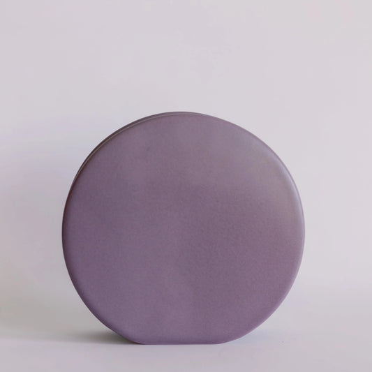 Ceramic circle bud vase in matte lavender, flat disc-shaped silhouette against pale grey backdrop