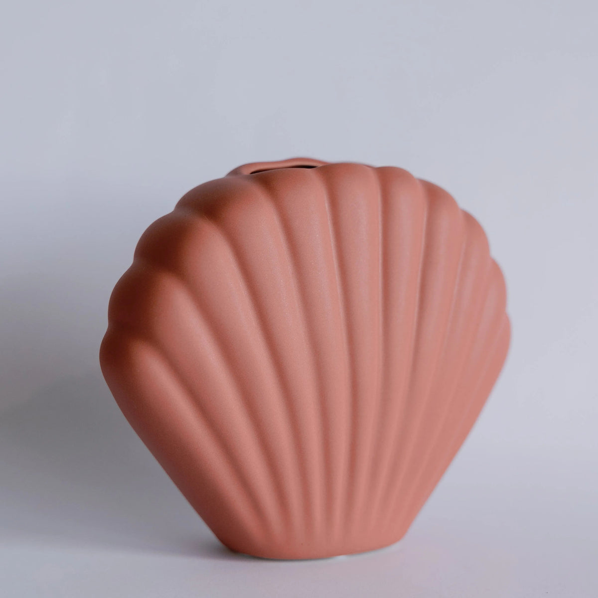 Terracotta pink ceramic bud vase shaped like a ribbed scallop seashell, matte finish