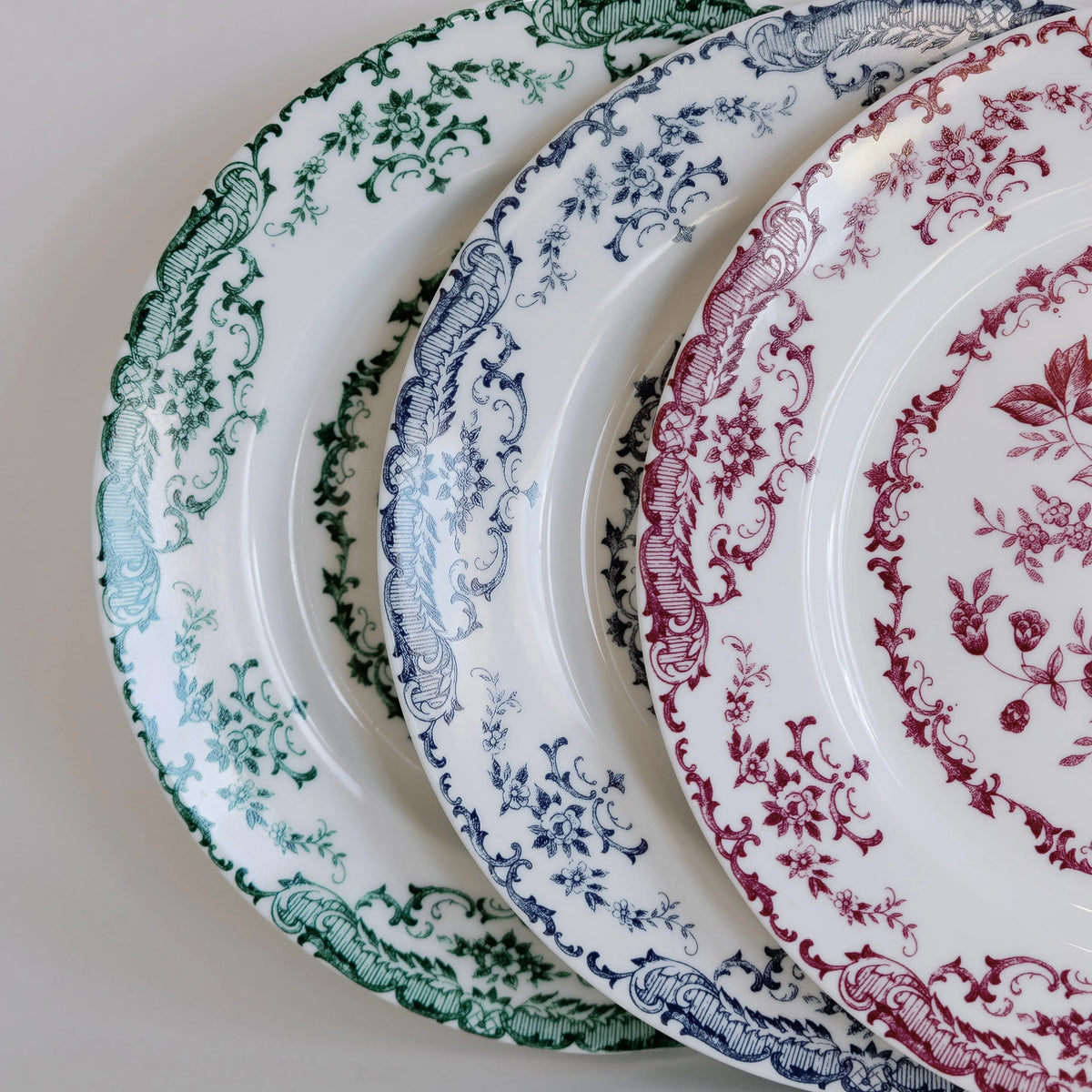 close up of floral pattern porcelain plates with magenta, navy, and forest green patterns