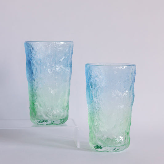 Two textured glass tumblers with a blue-to-green gradient, standing on a light gray studio background.