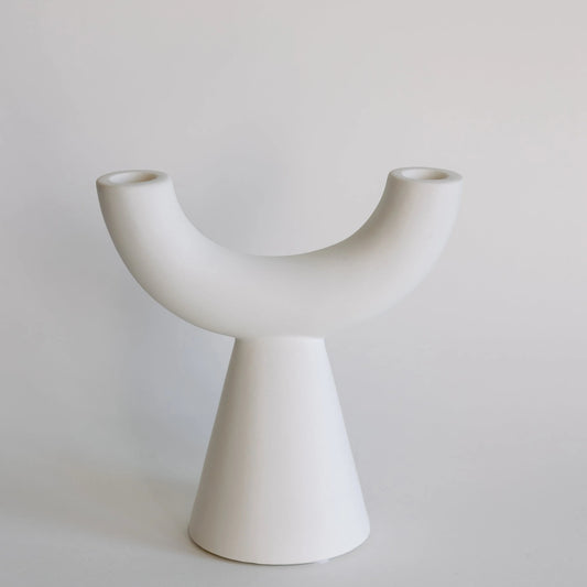 Crescent taper candle holder in matte white, curved U-arm with two taper cups on cone base
