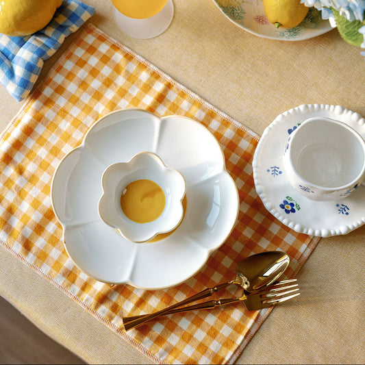 Daisy Bloom flower-shaped plates with yellow centers on yellow gingham, styled with lemons and gold flatware.