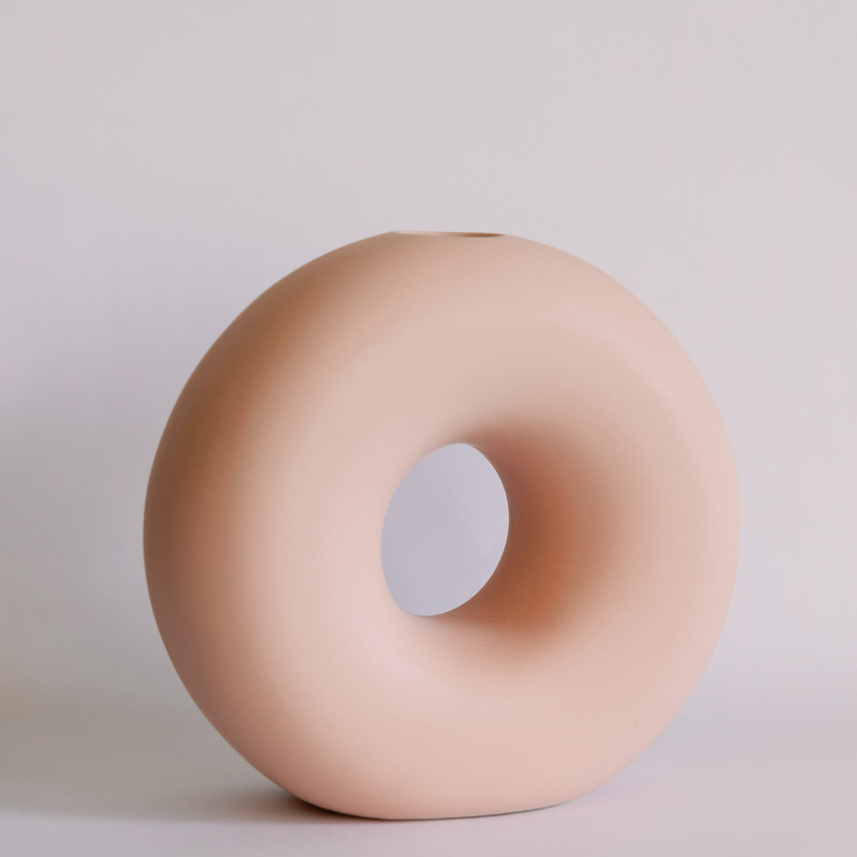 Peach blush ceramic donut bud vase, round ring shape with center hole and matte finish, front view