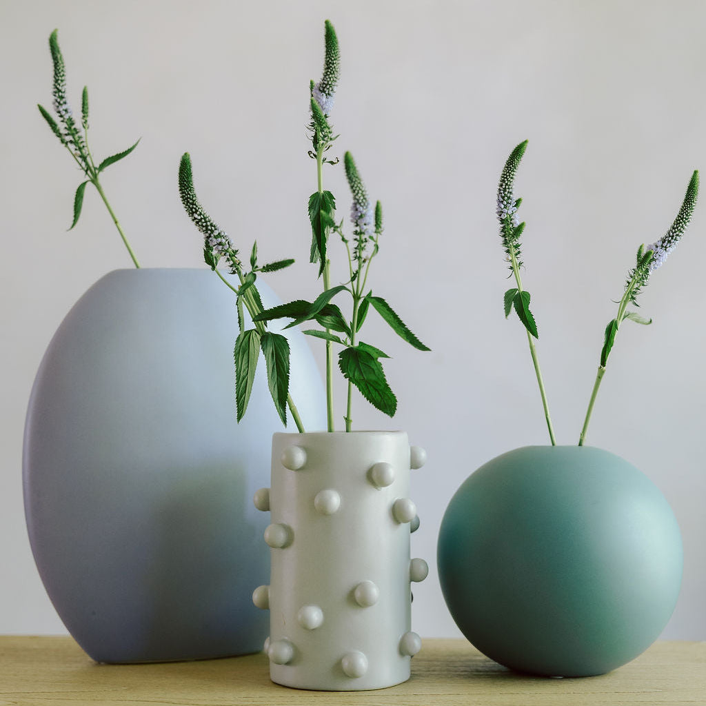 White dotted Dotty Cylinder Ceramic Vase grouped with blue and green vases holding veronica stems.