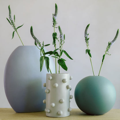 White dotted Dotty Cylinder Ceramic Vase grouped with blue and green vases holding veronica stems.