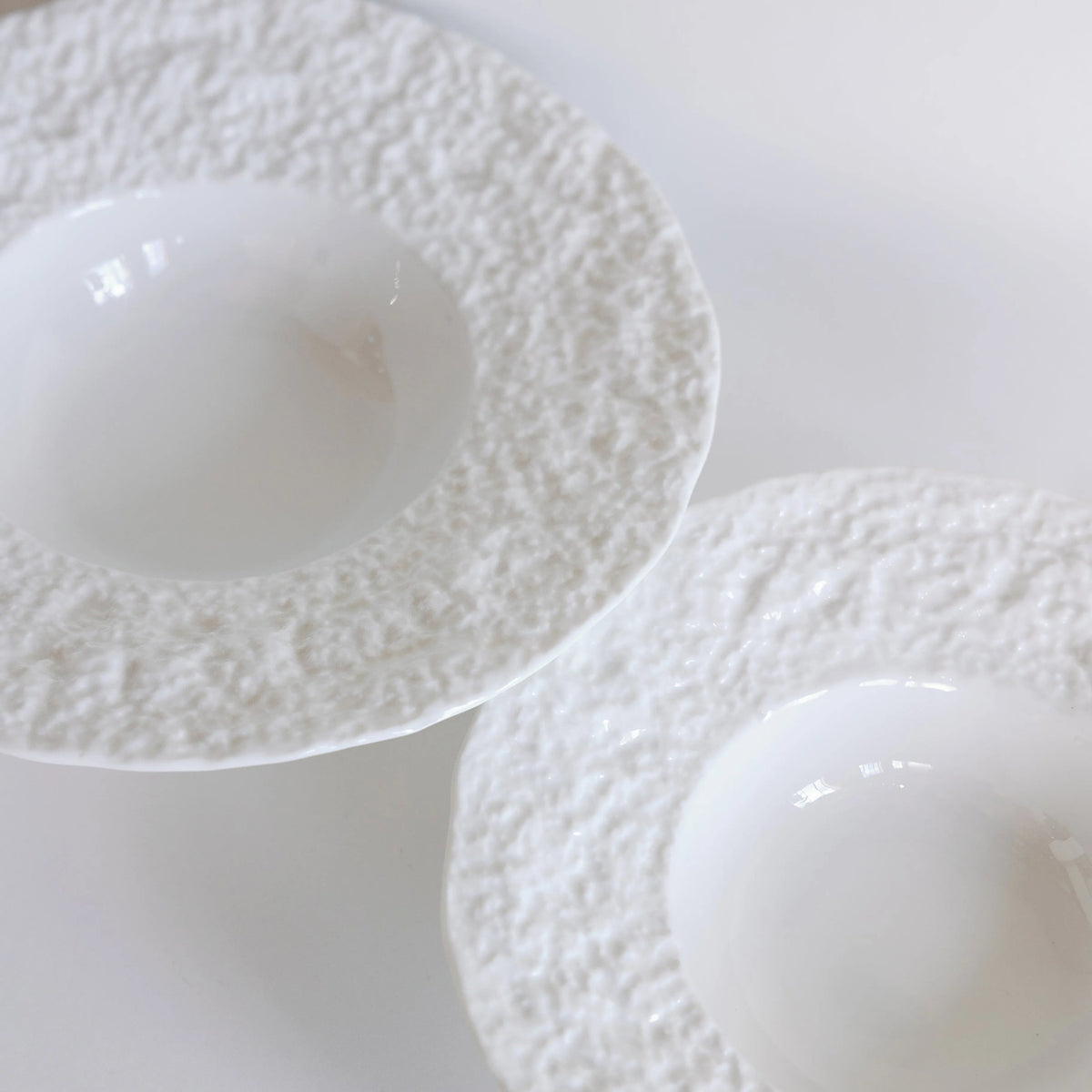 Two white snow-textured bowls side by side, close-up on their rough rims and glossy wells