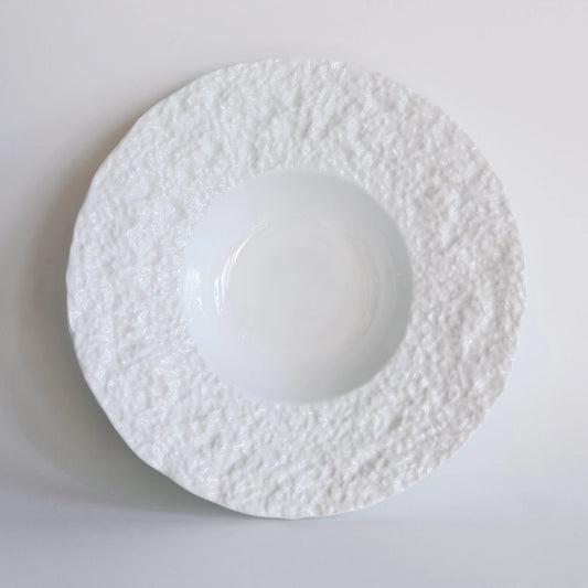 White textured bowl with wide snowy pebbled rim and deep glossy center, overhead view