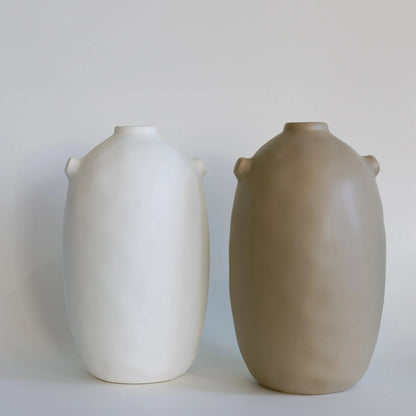 Two tall matte Kiln ceramic vases side by side in cream and taupe, with small nub handles at the neck