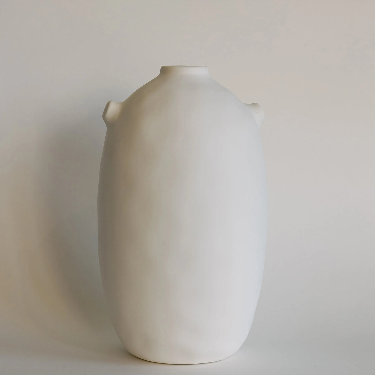 Tall cream-white Kiln ceramic vase with smooth matte body and tiny shoulder nubs, front view