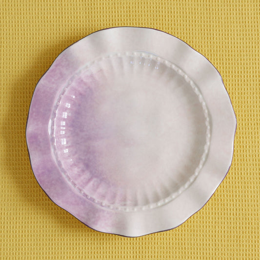 Round ceramic plate with purple interior on a yellow textured background