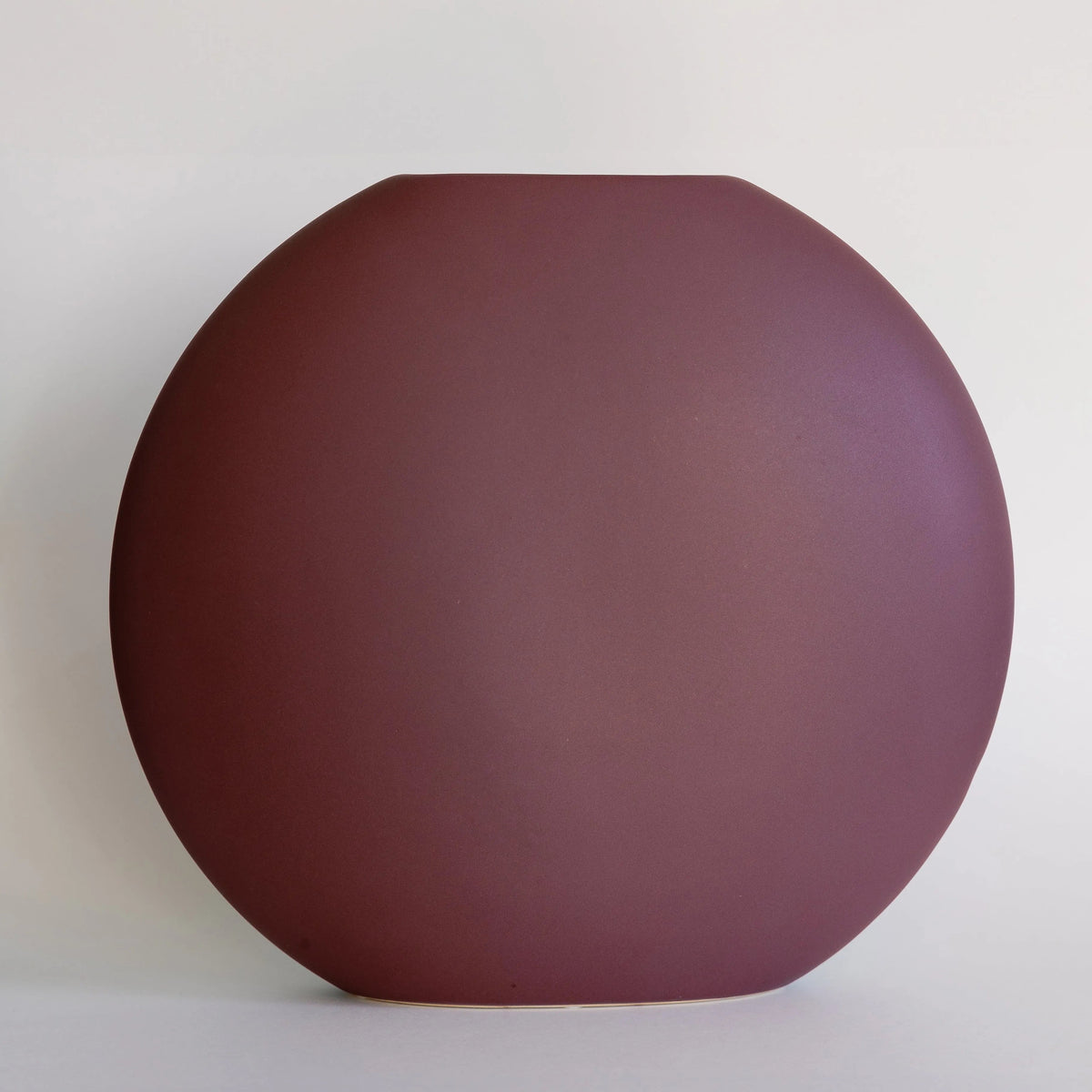 Luna ceramic vase in matte plum, round pebble-shaped form with slim slot opening, front view