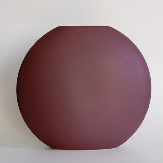 Luna ceramic vase in matte plum, round pebble-shaped form with slim slot opening, front view