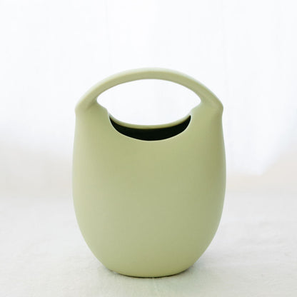Matte sage green ceramic basket bud vase with arched top handle, shown empty on a white backdrop.