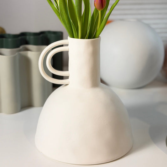 Carafe Ceramic Vase, cream bell-shaped vase with curved loop handle holding pink and orange tulips on a shelf.