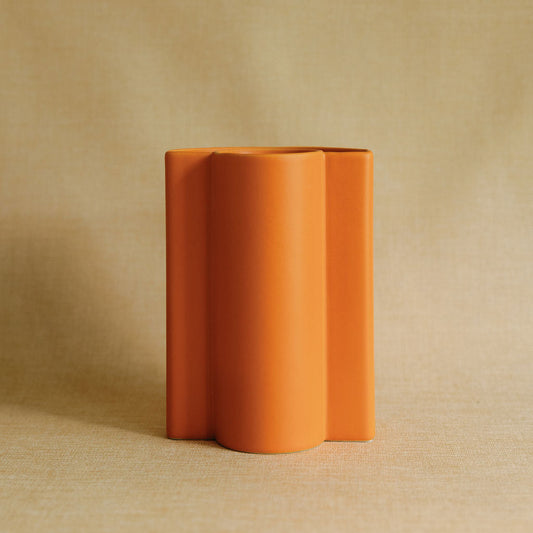 Orange ceramic vase on a beige background