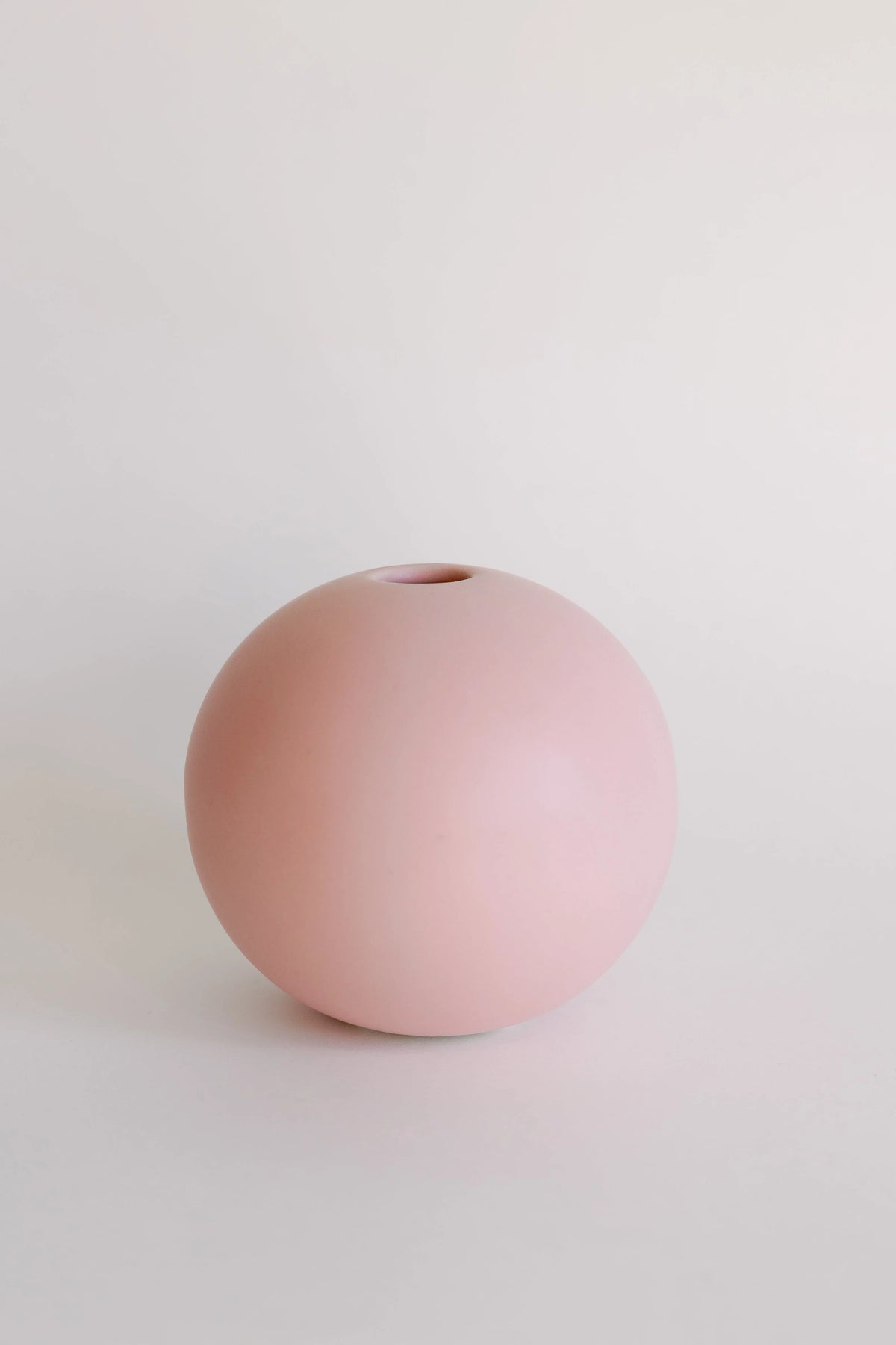 Mini orb bud vase in soft blush pink, round ceramic ball shape with small top hole on white