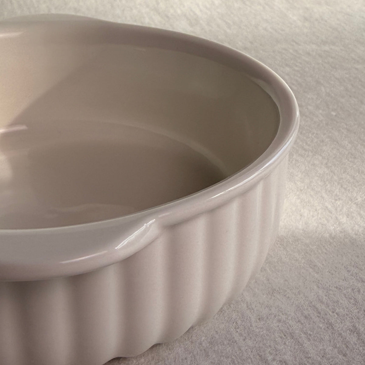 Close-up detail of the fluted ribbed exterior and handle on a cream ceramic baking bowl.