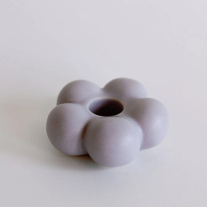 Lilac purple flower-shaped ceramic taper candle holder with rounded petals and center taper hole, full view