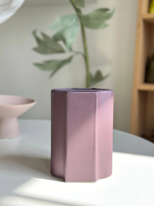 Plum Duo ceramic vase in mauve, faceted twin-column shape styled on a table with greenery behind