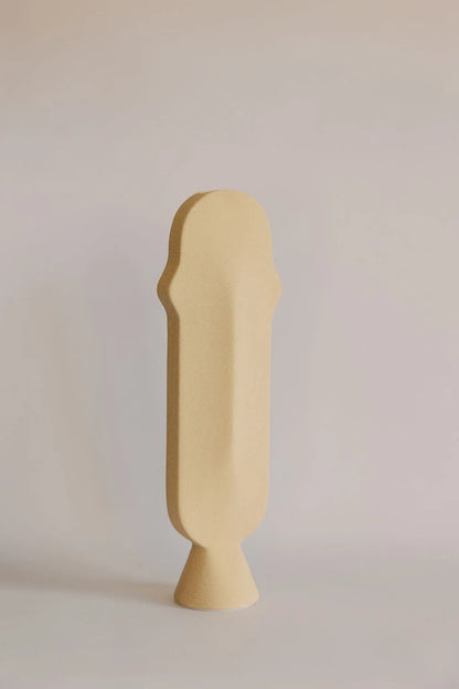 Tall narrow beige ceramic bud vase with arched profile on a small footed base