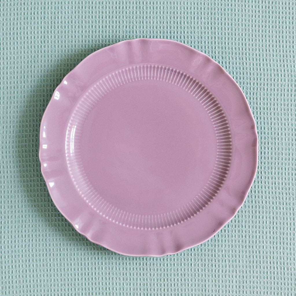 Mauve Provence Pleated porcelain plate with ribbed band and scalloped edge on a pale green waffle cloth.