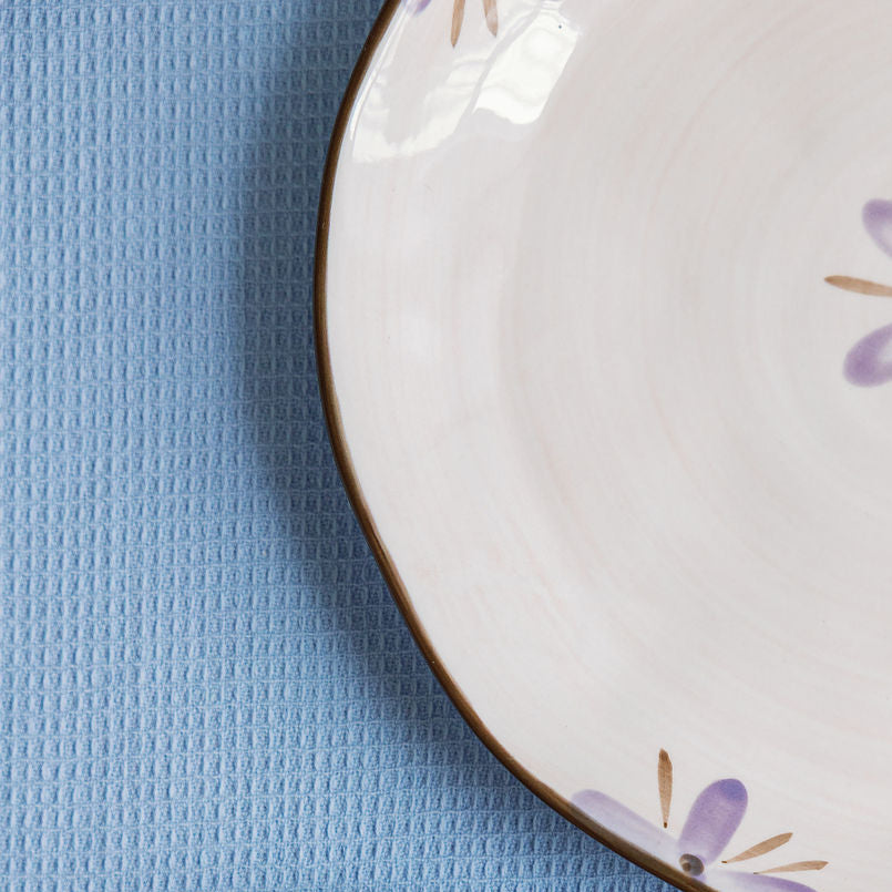 Two ceramic plates with floral designs on a blue textured surface