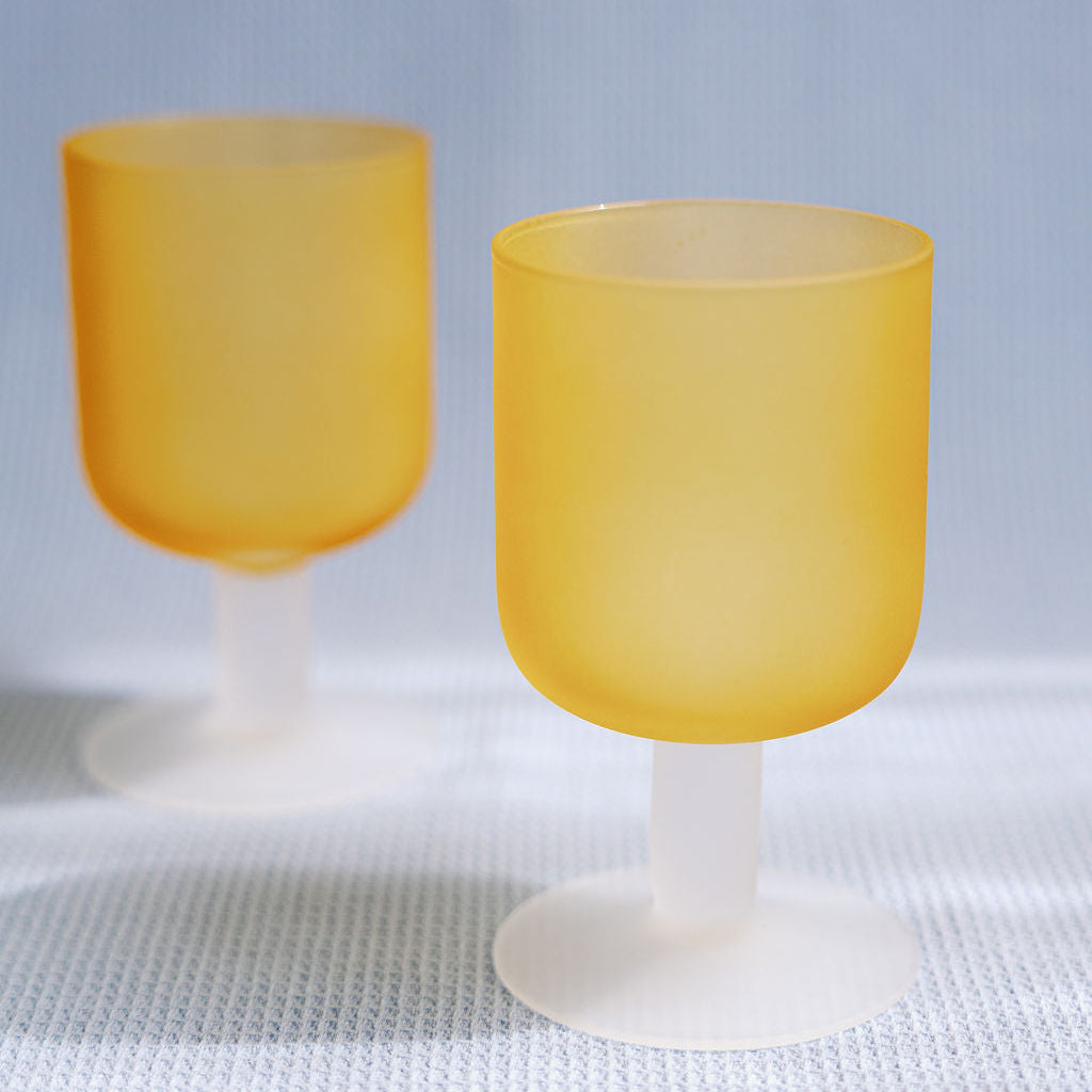 Two frosted amber Sea Glass stemmed goblets with white stems on a textured white cloth, full product shot.