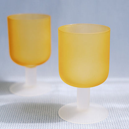 Two frosted amber Sea Glass stemmed goblets with white stems on a textured white cloth, full product shot.