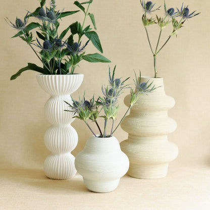 Cream Sediment ceramic bud vase with ribbed texture, grouped with two other neutral vases and thistle stems.