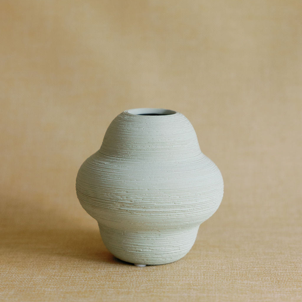 Green ceramic vase on a beige background