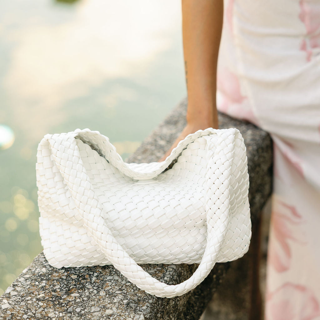White textured handbag on a stone surface with a blurred natural background