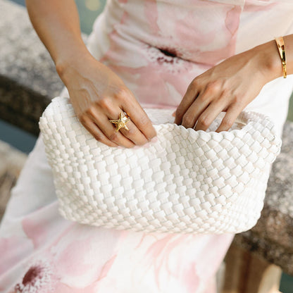 Sicily Leather Tote Bag in white held by a woman in a floral dress, scalloped woven edge in close-up.