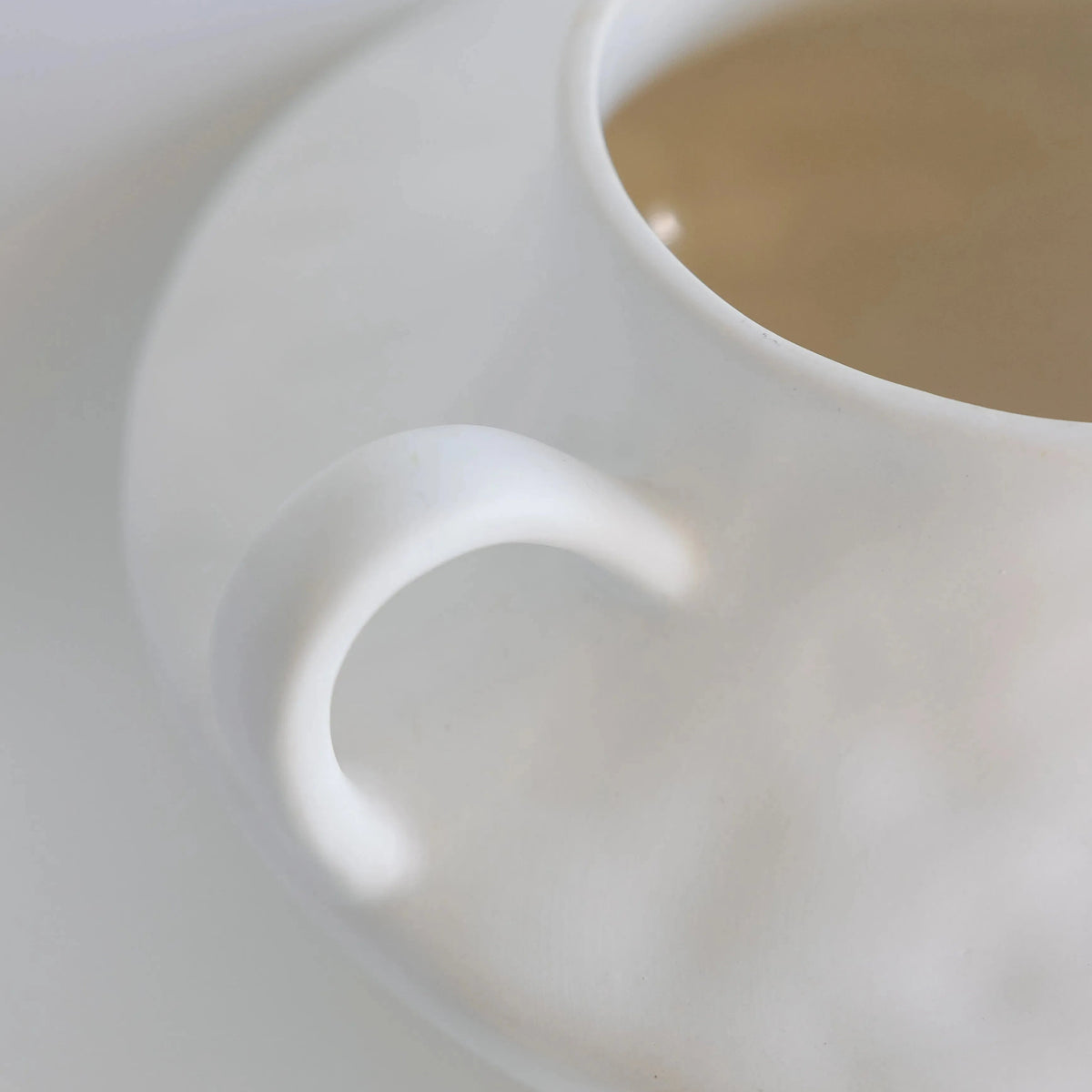 Cream-white stout amphora ceramic vase from above, detail of looped handle and rounded matte body